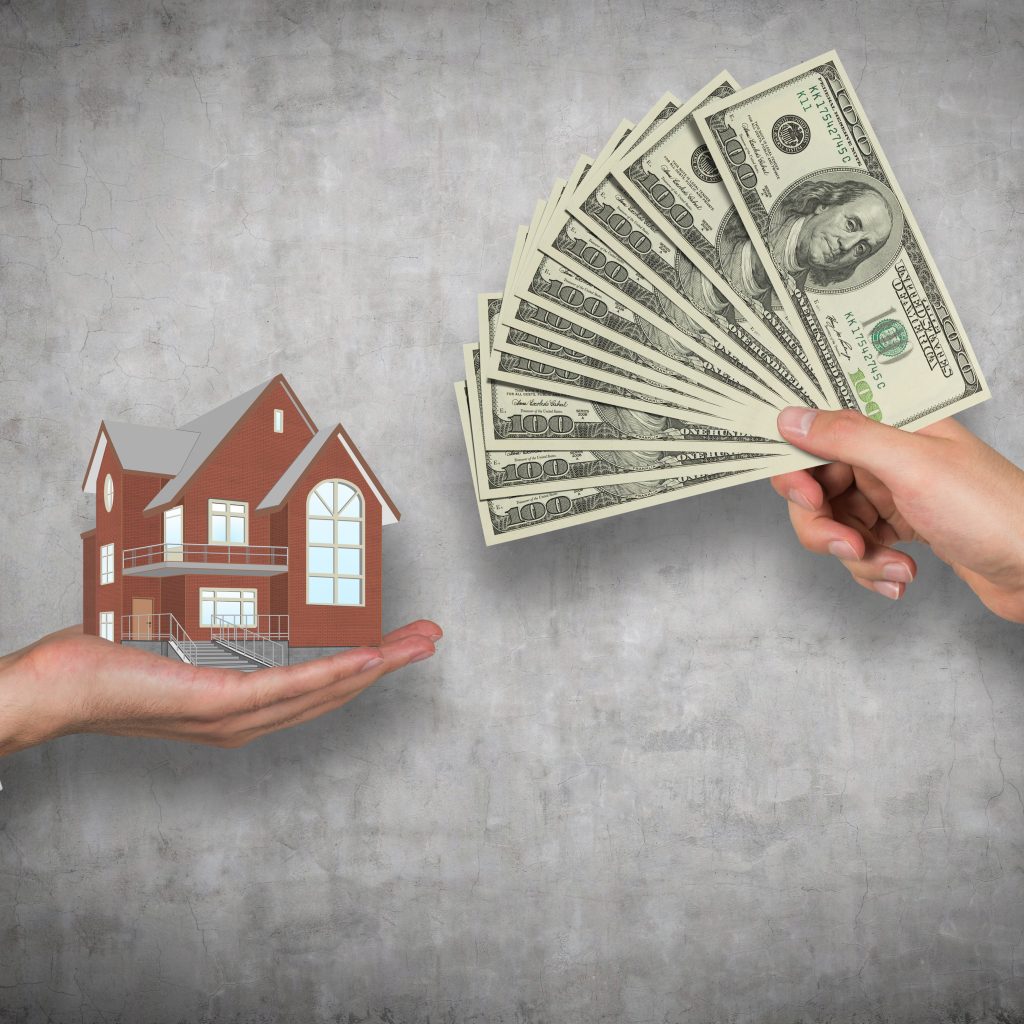 hand giving money for housing on a gray background